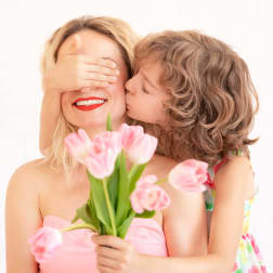 Woman holding pink tulips while a child kisses her cheek
