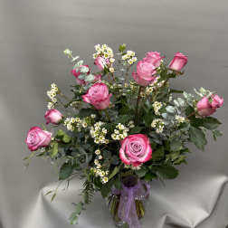 Pink roses arranged in a clear glass vase with small white filler flowers