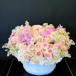 Large pastel rose arrangement in a white bowl vase