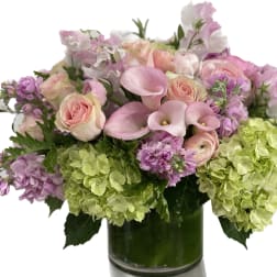 Pink roses and calla lilies with lavender blooms in a glass vase