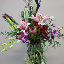 Tall bouquet of lilies, roses, and orchids in a vase