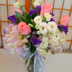 Bouquet of pink and white roses with purple flowers in a glass vase