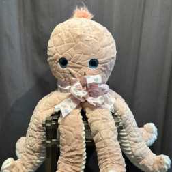 Plush octopus toy with a ribbon bow sitting on a chair