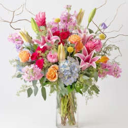 Mixed bouquet of pink, purple, and orange flowers in a clear glass vase