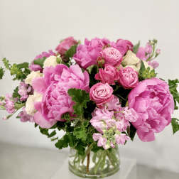Pink peonies and roses arranged in a clear glass vase