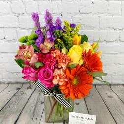 Colorful mixed bouquet in a glass vase with a striped ribbon