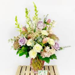Lavender and white flower arrangement in a pink glass vase