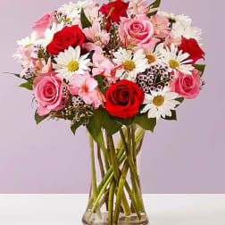 Bouquet of red and pink roses with white daisies in a glass vase