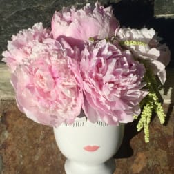 Pink peonies arranged in a white face-shaped vase