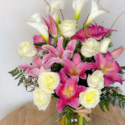 Pink lilies and white roses arranged in a glass vase