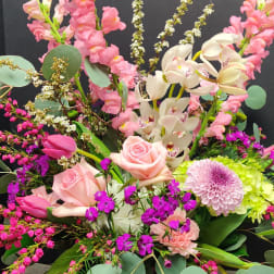 Pink and white mixed flower arrangement in a burgundy vase