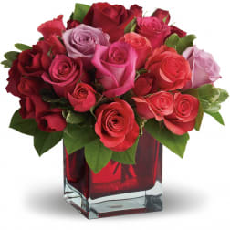 Bouquet of red, pink, and lavender roses in a red glass vase