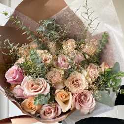 Bouquet of blush and peach roses wrapped in brown and white paper