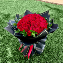 Large bouquet of red roses wrapped in black paper with a red ribbon