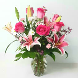 Pink roses and lilies arranged in a clear glass vase