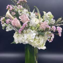 Tall vase arrangement with white hydrangeas, pink roses, calla lilies, and mixed white and pink blooms