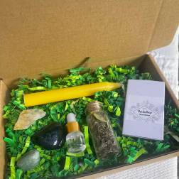 Gift box with a yellow candle, crystals, a dropper bottle, and a small herb vial