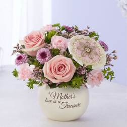 Pink rose bouquet in a cream vase with a decorative plaque