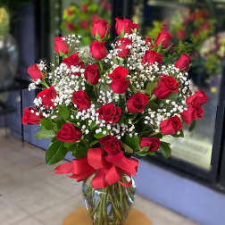 Bouquet of red roses and baby's breath in a glass vase with a red ribbon