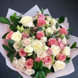 Bouquet of pink and cream roses wrapped in pale paper