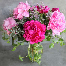 Pink peonies arranged in a clear glass vase with airy filler flowers