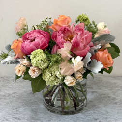 Mixed pink and peach flower arrangement in a clear glass vase