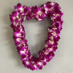 Heart-shaped purple orchid lei hanging on a wall