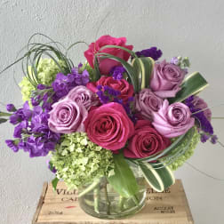 Bouquet of pink and lavender roses with purple flowers in a glass vase