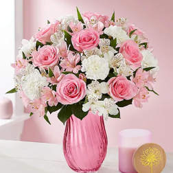 Pink roses and white flowers arranged in a pink glass vase