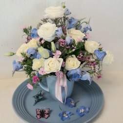 Bouquet of white roses and blue flowers in a light blue mug