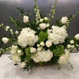White floral arrangement with roses and hydrangeas in a basket