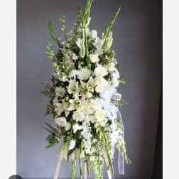 Tall white floral standing spray on an easel with ribbon