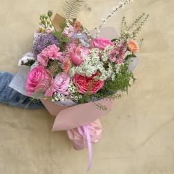 Hand-tied bouquet of pink and purple flowers wrapped in paper