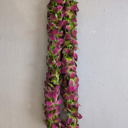 A hanging garland of purple flowers against a plain wall