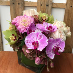 Pink and purple orchid bouquet in a square glass vase