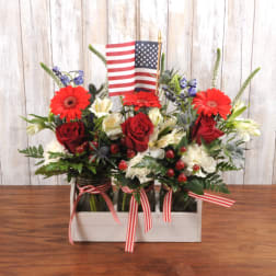 Patriotic red, white, and blue flower arrangement in mason jars with a small American flag.