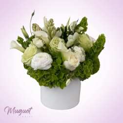 White and green floral arrangement in a white cylindrical vase