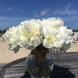 White peony bouquet in a clear glass vase on a table