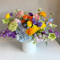 Colorful mixed bouquet in a white vase with roses and hydrangeas