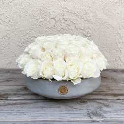 White roses arranged in a low gray bowl with a gold accent