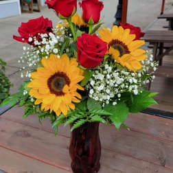 Red roses and yellow sunflowers in a dark glass vase