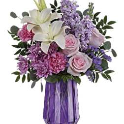Lavender and pink bouquet with white lilies in a purple vase