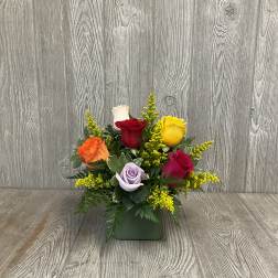 Mixed roses in a green square vase with yellow filler flowers