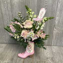 Pink roses and lilies arranged in a decorative boot vase