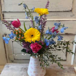 Mixed bouquet in a white vase with yellow daisies and pink tulips