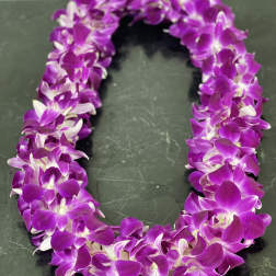 Purple orchid lei on a dark surface