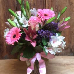 Pink and white mixed bouquet in a glass vase with a pink ribbon