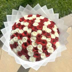 Round bouquet of red and white roses wrapped in translucent paper