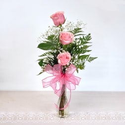 Pink roses in a clear glass vase with a pink ribbon bow