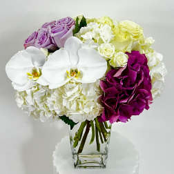 Bouquet of white orchids, hydrangeas, and roses in a clear glass vase